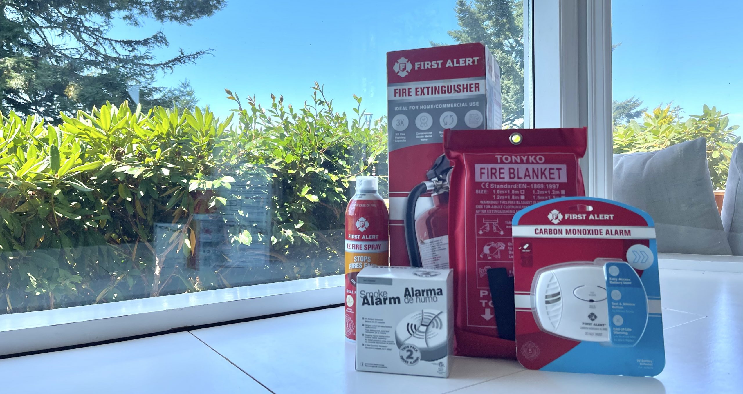 A group of fire safety equipment including fire extinguishers, smoke alarm, and a fire blanket for kitchen fires