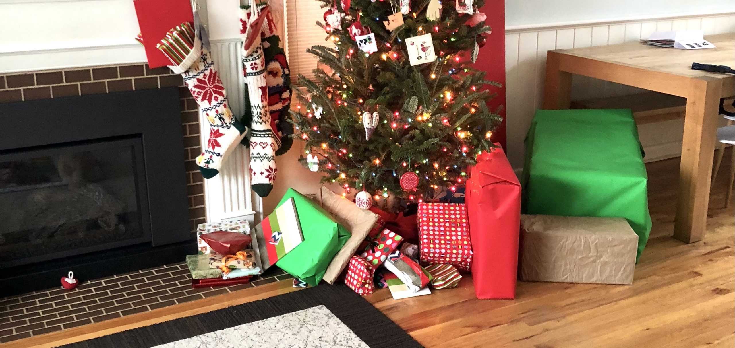 green, red, and brown wrapped packages under a christmas tree